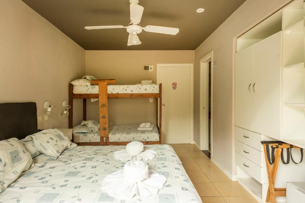 Une chambre avec des lits superposés, un ventilateur de plafond, une armoire et un lit avec des serviettes.