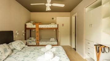 Une chambre avec des lits superposés, un ventilateur de plafond, une armoire et un lit avec des serviettes.