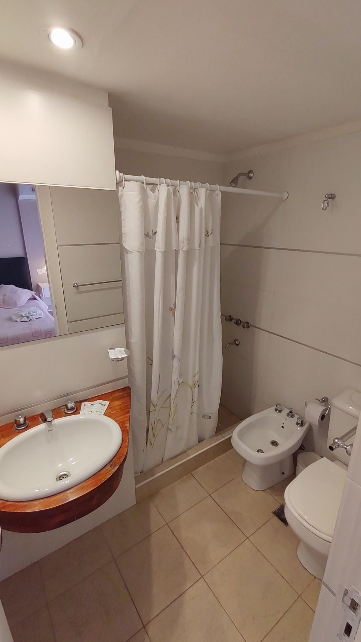 Une salle de bain équipée d’un lavabo, d’un bidet, de toilettes et d’un rideau de douche.