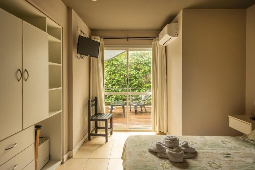 Una camera da letto con un letto, una TV a muro, un armadio e un balcone con mobili da esterno.