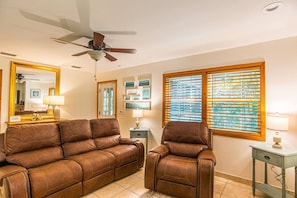 A room with a brown leather sofa, a matching armchair, a ceiling fan, a window with blinds, and a small table with a lamp. - *New*Homosassa Captain`s Quarters~Sleeps 8|Patio (Homosassa)