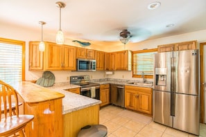 A kitchen with wooden cabinets, stainless steel appliances, granite countertops, and pendant lighting. - *New*Homosassa Captain`s Quarters~Sleeps 8|Patio (Homosassa)