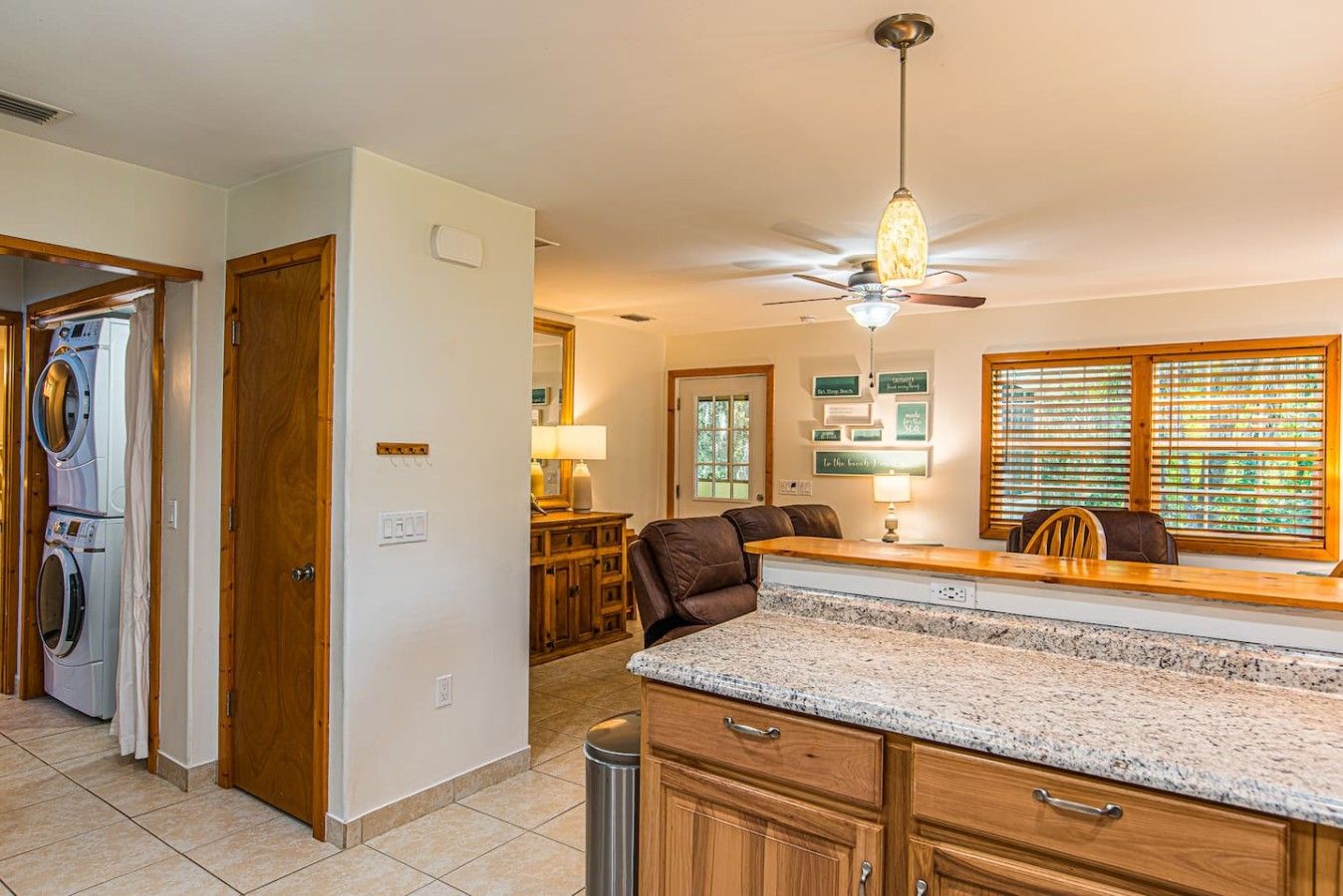 A kitchen with granite countertops, wooden cabinets, a ceiling fan, and a dining area with a table and chairs.