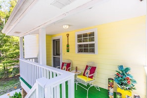 A porch with a white railing, a yellow wall, and a metal chair with a red cushion. - *New*Homosassa Captain`s Quarters~Sleeps 8|Patio (Homosassa)
