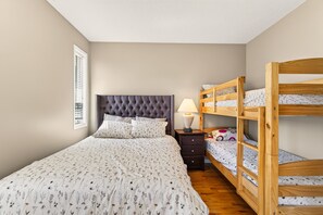 A bedroom with a single bed, a nightstand, a lamp, and a wooden bunk bed. - Oceanview Retreat + Private Games Room (Nanaimo)