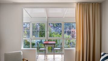 A room with a large window, a table, two chairs, and a sofa.