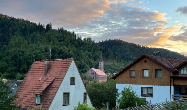 A village with traditional houses, a church, and a forested hill in the background.