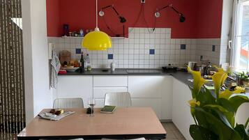 Eine moderne Küche mit weißen Schränken, einer roten Akzentwand und einer gelben Pendelleuchte.
