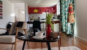 A living room with a dining table, a chair, a coffee table, and a vase with flowers.