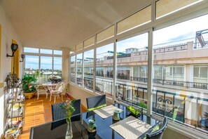 A balcony with a table and chairs, a potted plant, and a view of buildings. - Tranquil Tides España  - 3 bed Appt Punta Prima (Orihuela)