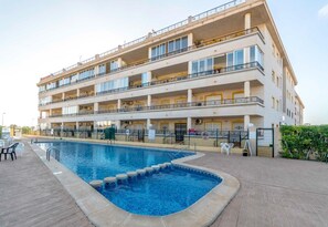 Ett hotell med flera våningar, en swimmingpool, utomhusservering och balkonger.