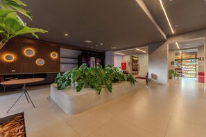 A modern lobby with a central planter, seating area, and a snack bar. - On Augusta by Bhomy (São Paulo)