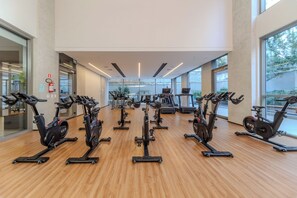 A gym with multiple exercise bikes and treadmills, large windows, and a wooden floor. - On Augusta by Bhomy (São Paulo)