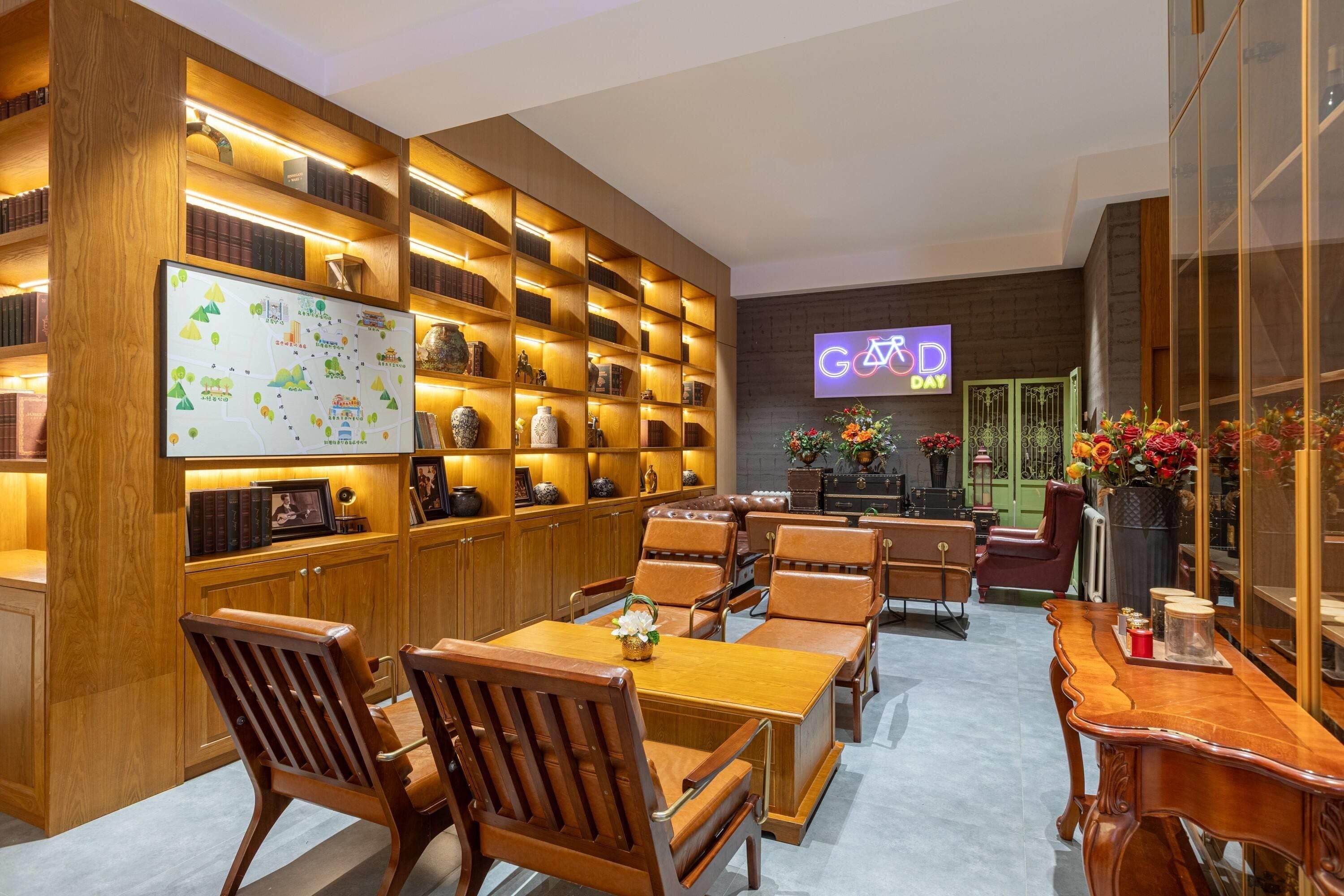 A library with wooden bookshelves, a whiteboard, and a seating area with tables and chairs.