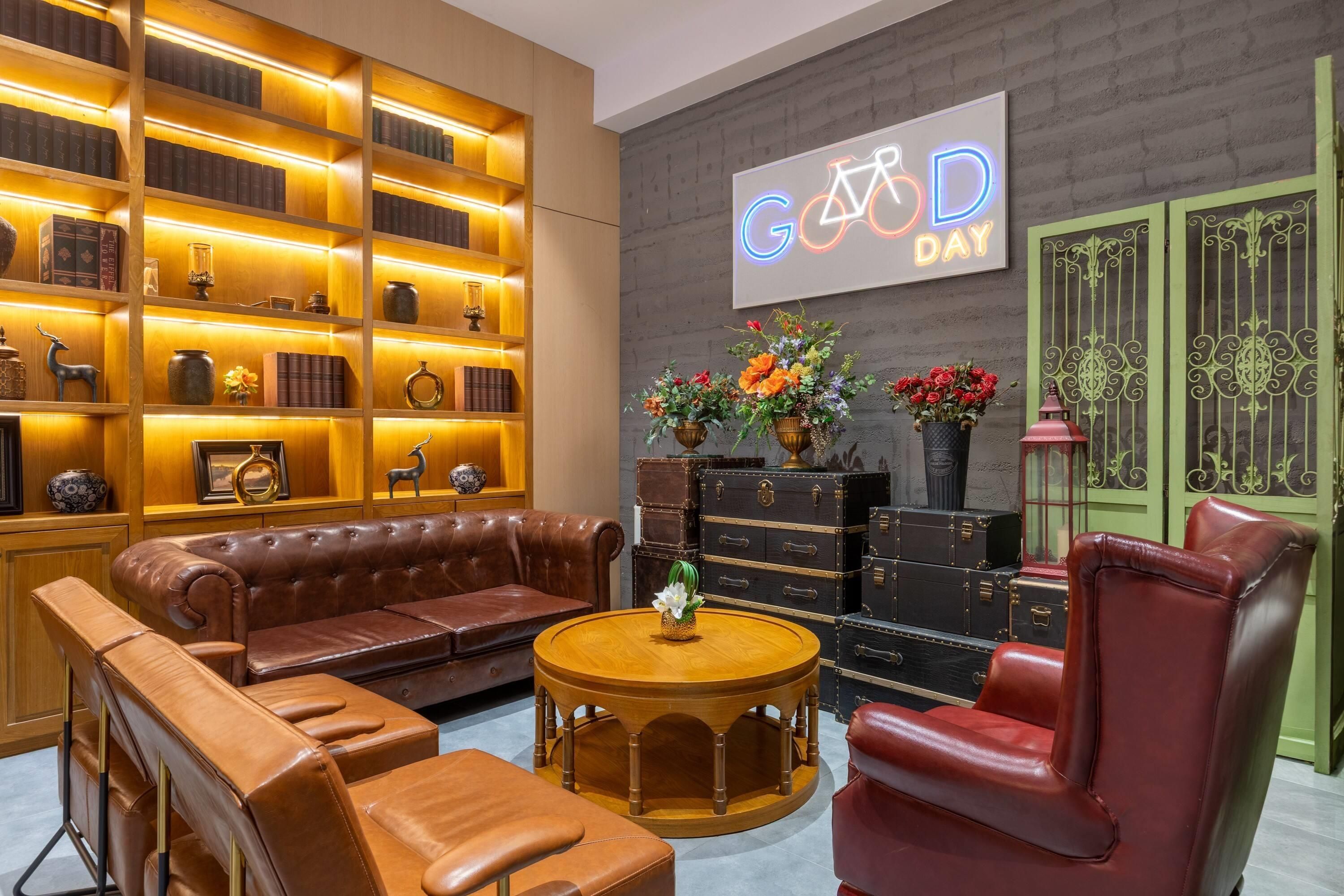 A cozy lounge area with leather sofas, a round wooden coffee table, and a bookshelf with books and decorative items.