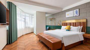 Quarto de hotel com uma cama grande, um banco, uma televisão e uma peça de arte de bicicleta na parede.
