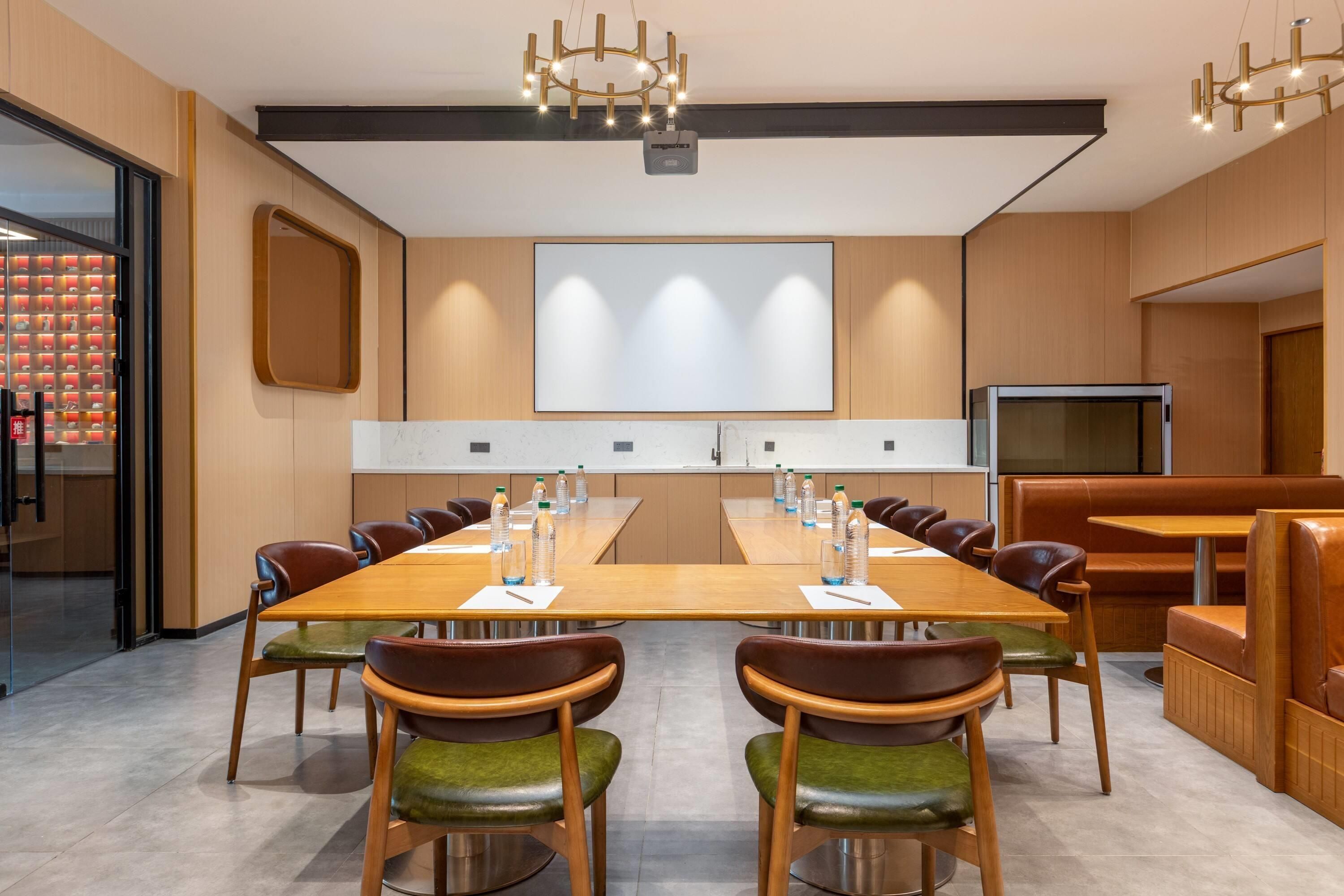 A conference room with a long table, chairs, a projector screen, and a television.