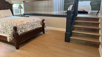 A bedroom with a wooden bed, a staircase, and a view of the outdoors.