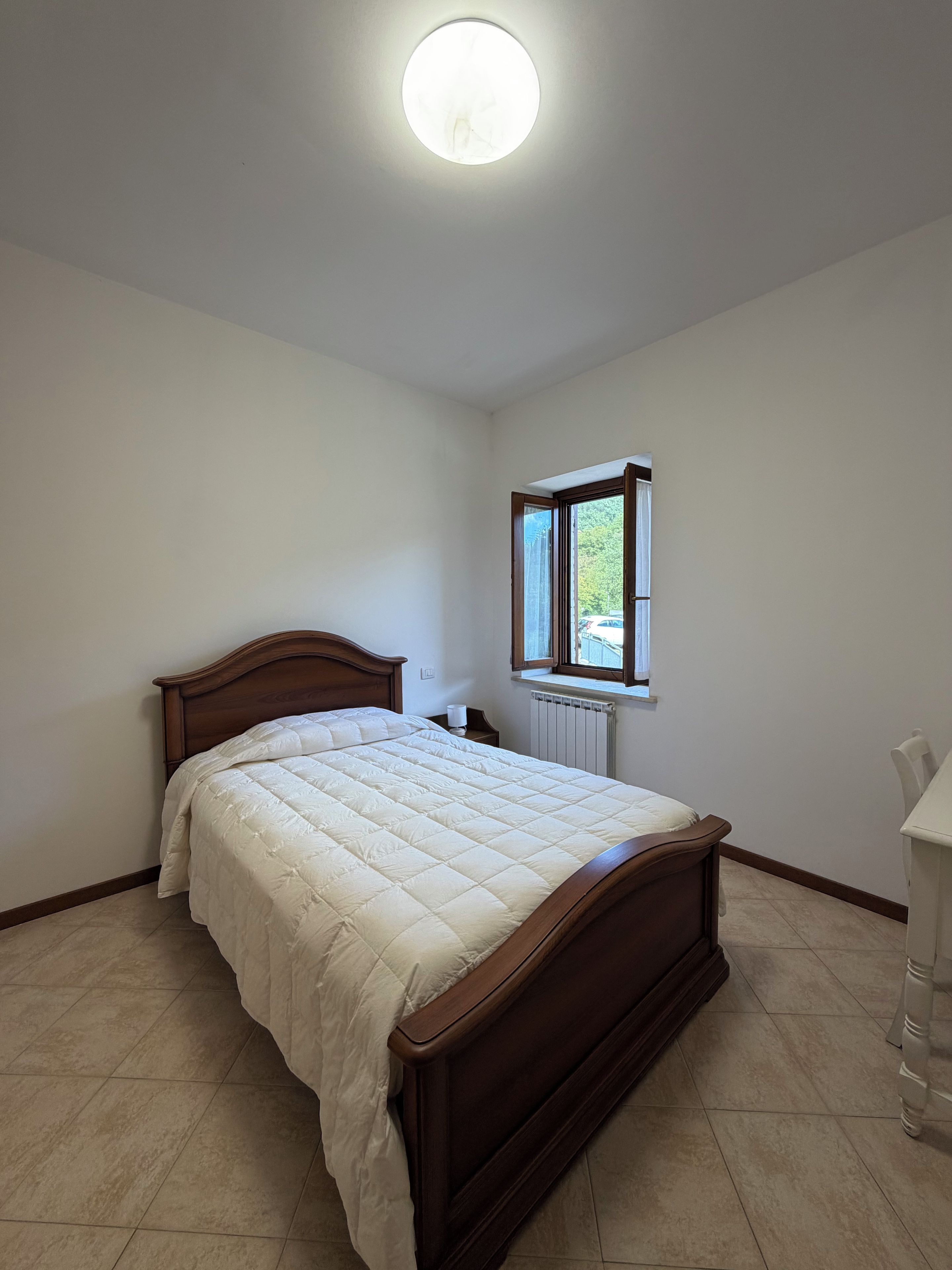 A bedroom with a wooden bed, a window, and a radiator.