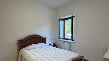 A bedroom with a wooden bed, a window, and a radiator.