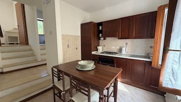 A kitchen with a dining table and chairs, a stove, cabinets, and a window.