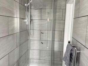 Eine moderne Dusche mit Duschbrause und Handtuchhalter mit Handtuch.