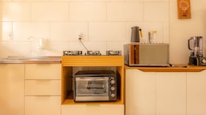 Eine kleine Küchenzeile mit einem Toaster, einer Kaffeemaschine und einem Mixer auf der Arbeitsfläche.