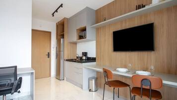 A modern kitchen with a built-in refrigerator, a coffee machine, and a flat-screen TV mounted on the wall.