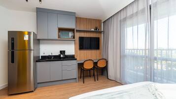 Een moderne hotelkamer met een kitchenette, een bed en uitzicht op de omgeving.