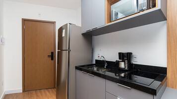 A compact kitchen with a built-in refrigerator, a coffee maker, and a microwave.