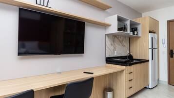 A modern kitchen with a built-in TV, wooden cabinets, a black countertop, and a stainless steel sink.