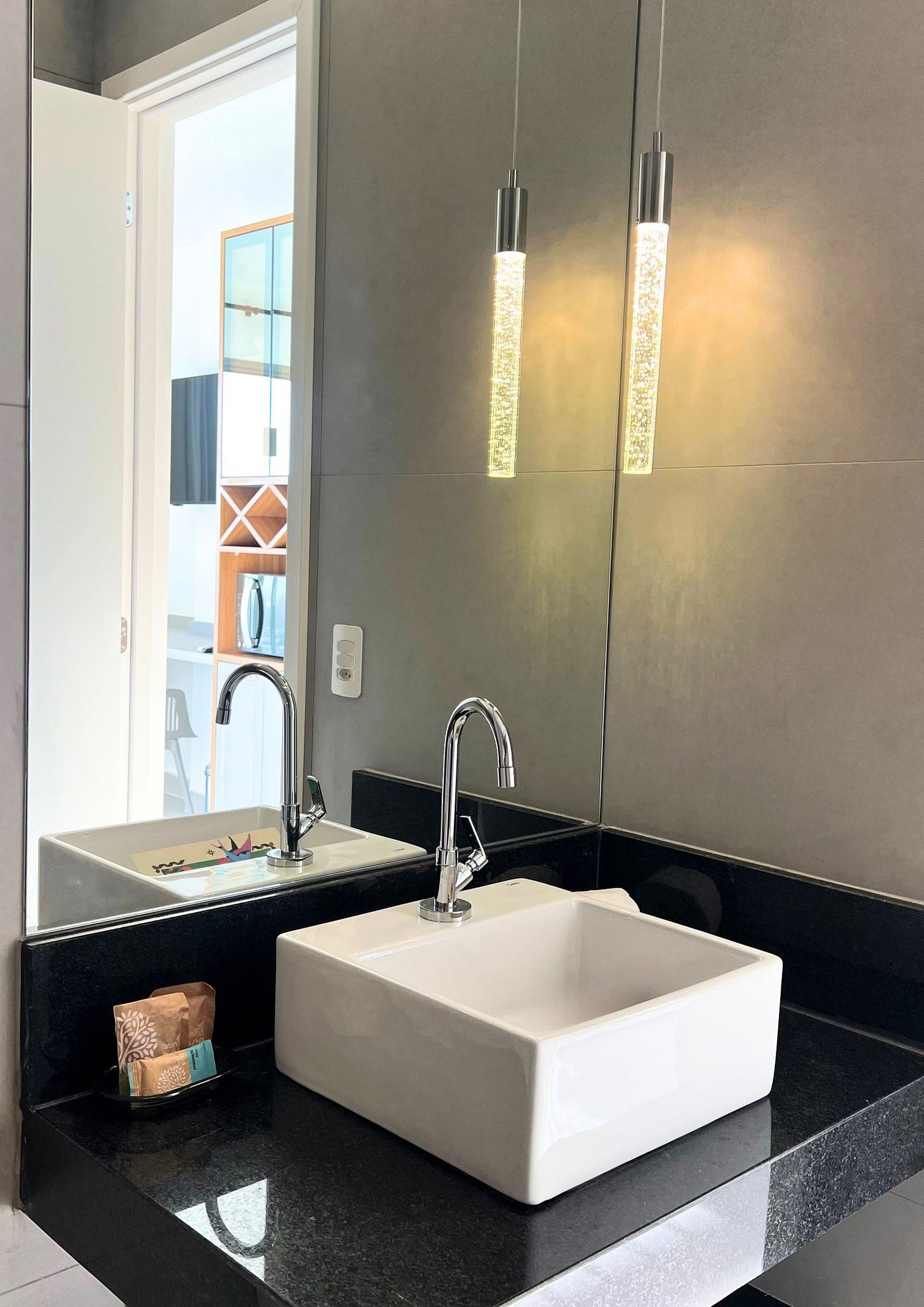 A modern bathroom with a white sink, two faucets, and a large mirror.