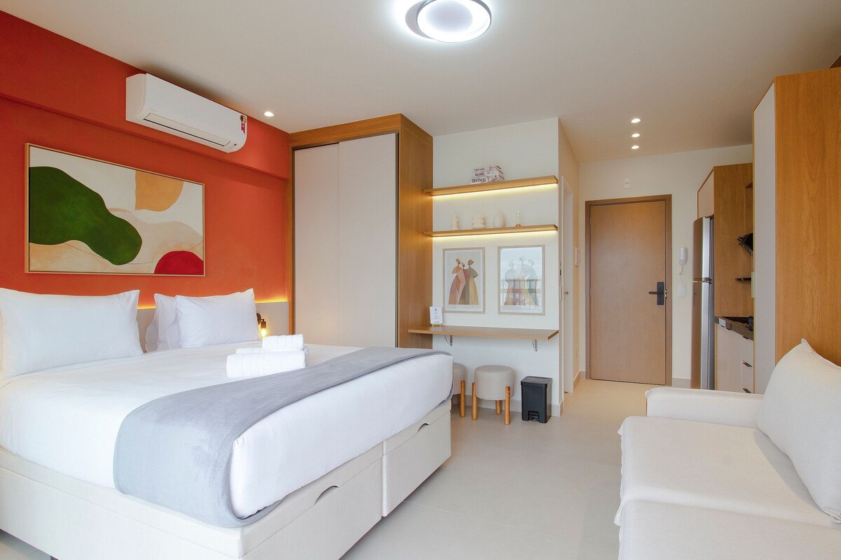 Una habitación de hotel con cama, mesitas de noche, zona de estar y armario.