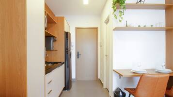 Een functionele keuken met een koelkast, kastjes en een eethoek met een tafel en stoelen.