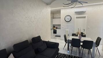 Ein modernes Wohnzimmer mit einer schwarzen Couch, einem Couchtisch und einem Essbereich mit Stühlen und einem Tisch.