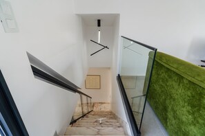 A staircase with a glass railing, a green carpeted wall, and a marble floor. - GuestReady-Luxurious Retreat in Câmara de Lobos (Câmara de Lobos)
