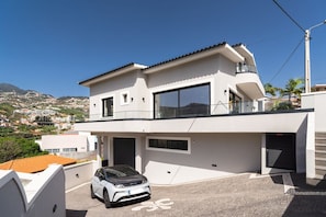 A modern two-story house with a car parked in the driveway. - GuestReady-Luxurious Retreat in Câmara de Lobos (Câmara de Lobos)
