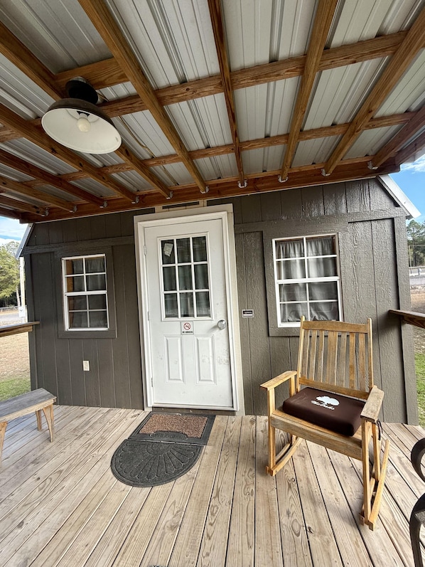 A wooden deck with a bench and a door with a 'No Smoking' sign.