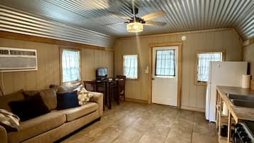 A compact living space with a kitchenette, a sofa, a dining table, and a ceiling fan.