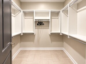 A walk-in closet with open shelving, a hanging rod, and a door. - Magic City Outlook | 2 Queen 2BR (Birmingham)