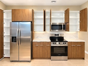 A modern kitchen with built-in appliances, wooden cabinets, and a marble countertop. - City Lights Haven | 2 Queen 2BR (Birmingham)