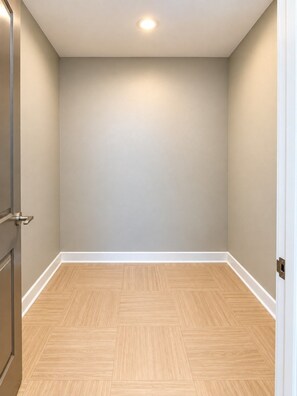 A room with a wooden herringbone floor, beige walls, and a white door. - The City Perch | Queen + Queen 2BR (Birmingham)