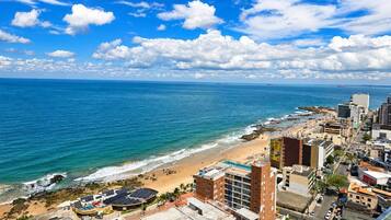 A coastal cityscape with a beach, buildings, and a clear sky.