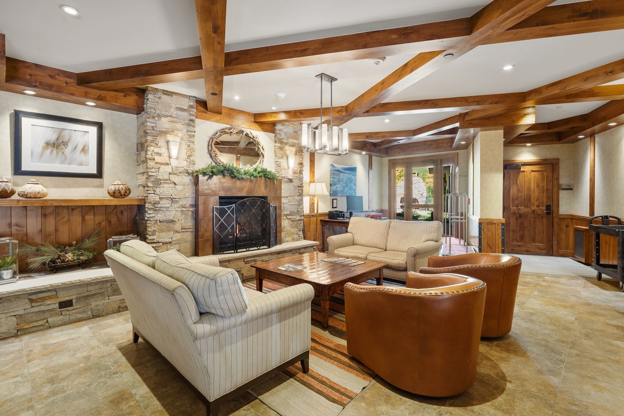 A spacious living room with a stone fireplace, wooden beams, and a comfortable seating area.