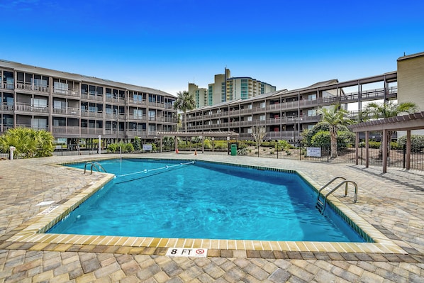 A hotel with a central swimming pool surrounded by multiple balconies. - Tilghman Beach 227 - 3BR Condo w/ Pool (North Myrtle Beach)