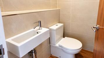 A bathroom with a white sink, a toilet, and a wooden door.