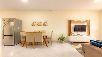 Uma sala de estar moderna com área de jantar, TV de tela plana e geladeira.