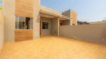 Um edifício residencial com um pátio ladrilhado, uma porta visível e uma janela.
