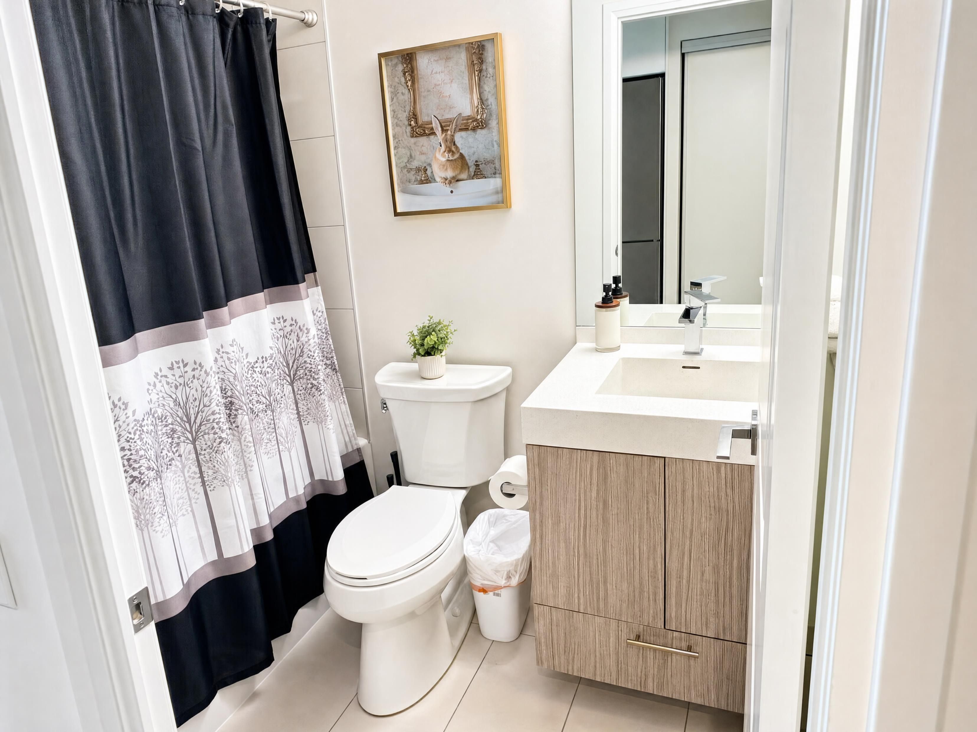 A bathroom with a toilet, sink, mirror, and a framed picture on the wall.