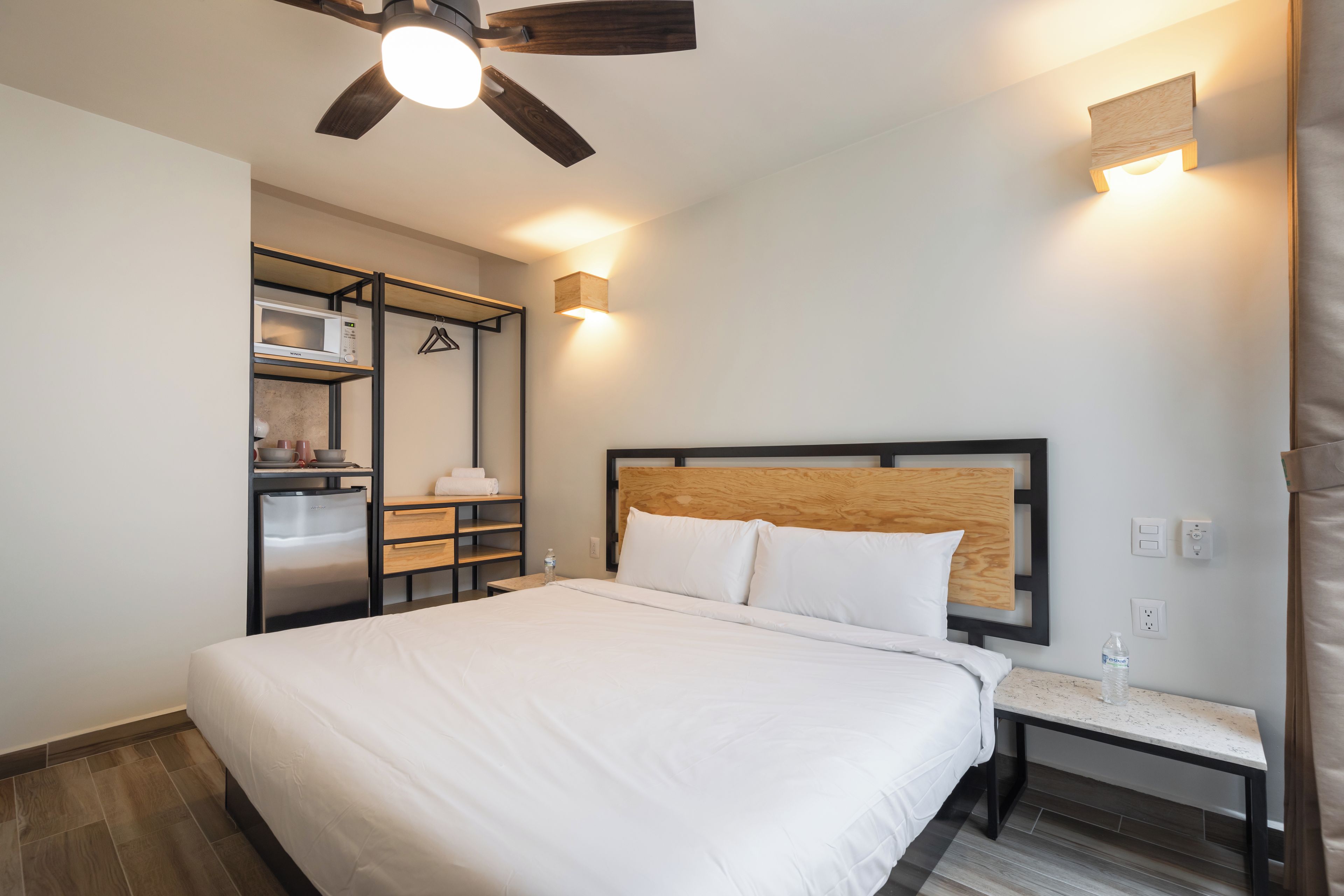 Habitación de hotel con cama, armario empotrado, una mesita y ventilador de techo.